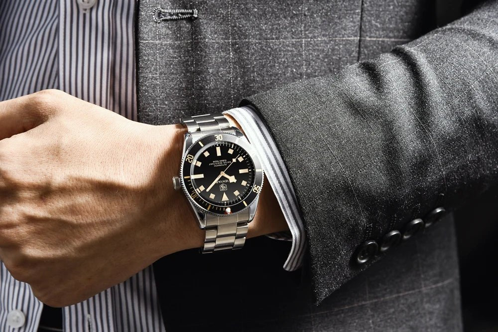 Reloj Benyar BB58 BY-5179M automático para hombre, puesto en muñeca con traje gris, caja y brazalete de acero y esfera negra.