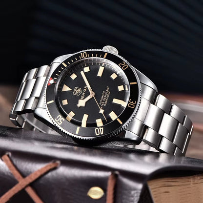 Reloj Benyar BB58 BY-5179M automático para hombre, caja y brazalete acero, esfera negra vintage, bisel giratorio y agujas luminiscentes, sobre libro.
