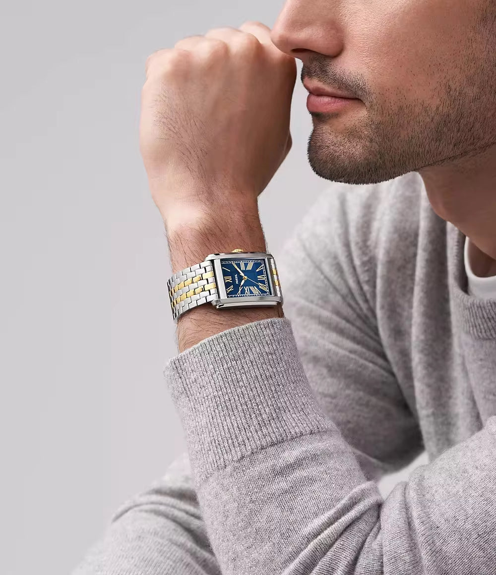 Reloj Fossil Carraway FS6010 bicolor, esfera azul, visto en la muñeca de un hombre con suéter gris, estilo elegante y moderno.