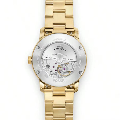 Vista trasera reloj Fossil Heritage ME3226 automático, caja dorada, maquinaria visible, detalles de acero y fondo blanco.