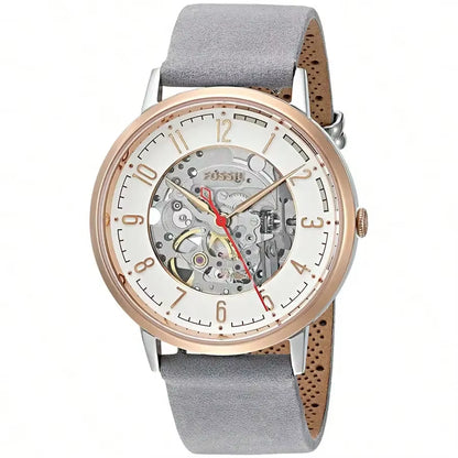 Reloj Fossil ME3131 automático skeleton, caja oro rosa, esfera abierta mostrando el mecanismo, correa gris y visualización en ángulo.