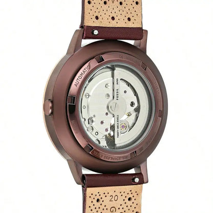 Vista trasera del Fossil ME3131 automático, caja color cobre/marrón, fondo transparente y correa perforada de piel marrón.