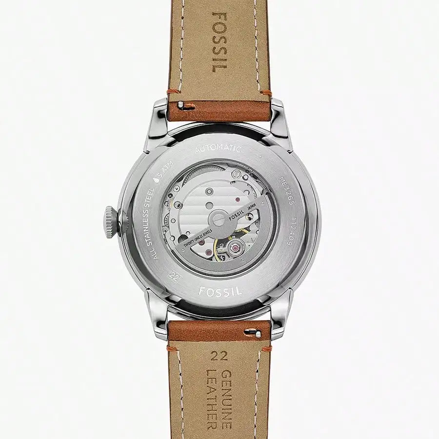 Vista trasera del reloj Fossil ME3265 automático con caja de acero, correa de cuero marrón y fondo transparente mostrando el movimiento.
