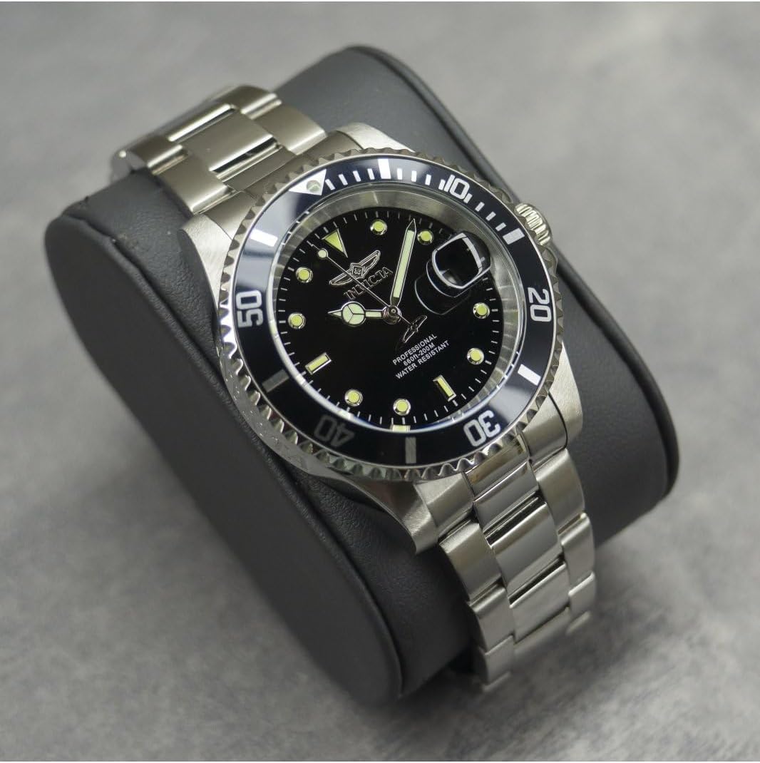 Reloj Invicta Pro Diver 26970, presentado sobre cojín negro, brazalete de acero y bisel negro, esfera luminosa.