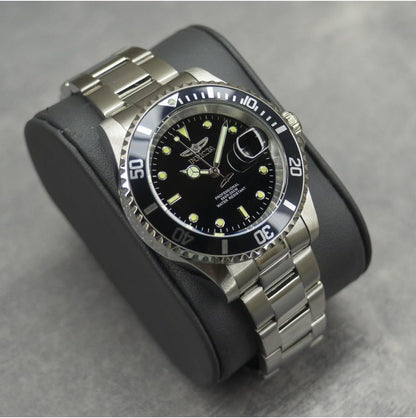 Reloj Invicta Pro Diver 26970, presentado sobre cojín negro, brazalete de acero y bisel negro, esfera luminosa.