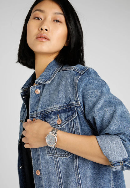 Reloj Tommy Hilfiger para mujer con brazalete de acero, mostrado en muñeca en un look casual con chaqueta vaquera.