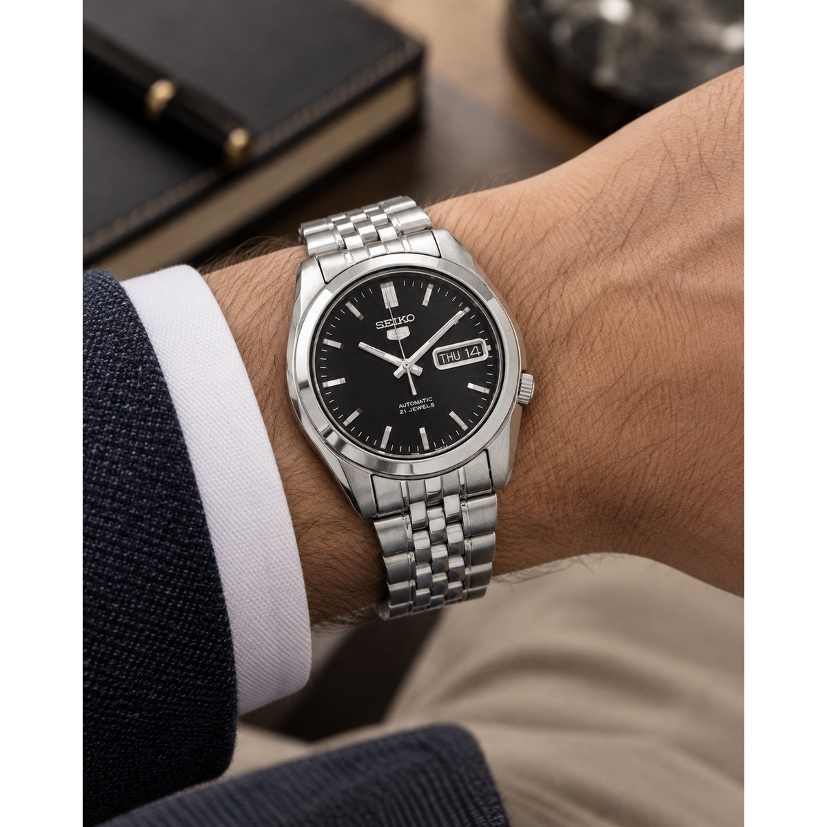 Seiko 5 SNK361K1 men's automatic watch featuring a black dial and stainless steel bracelet worn on the wrist.