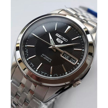 Seiko 5 SNKL23J1 men's automatic watch dial closeup showcasing the black vertically-striped dial and day-date window