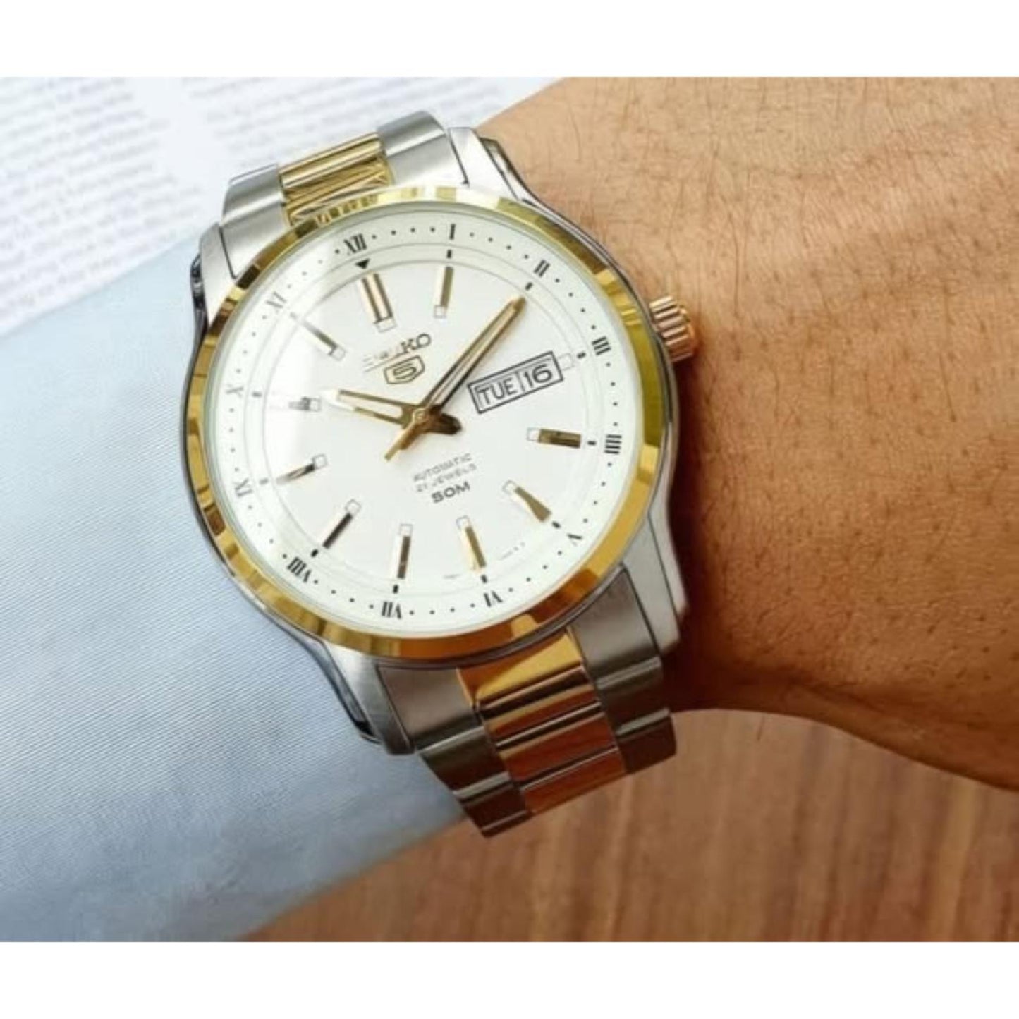 Seiko 5 SNKP14K1 automatic dress watch worn on wrist with white dial, gold-tone accents, day-date display and two-tone stainless steel bracelet.