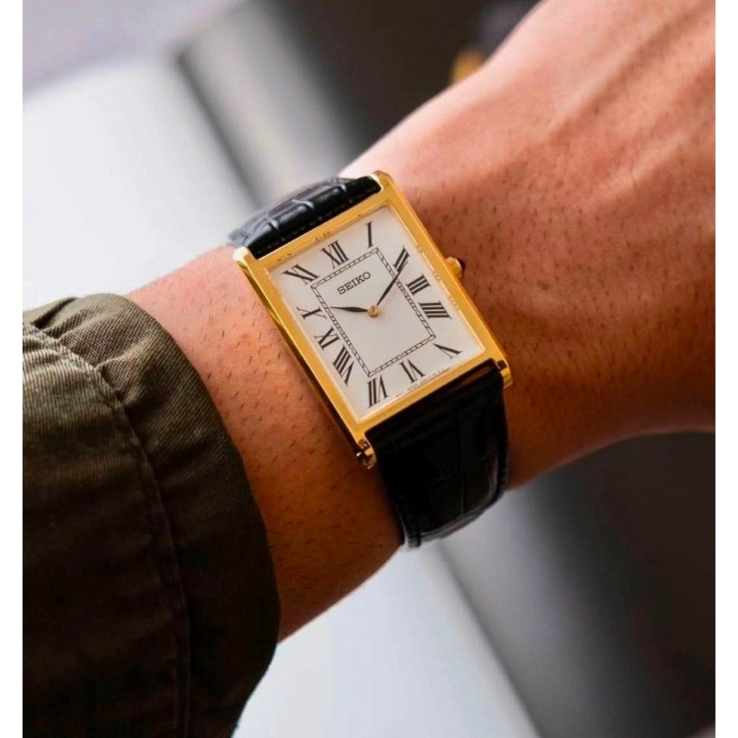 Seiko Classic SWR104P1 dress watch worn on the wrist, featuring a rectangular gold-tone case, white dial with Roman numerals, and black leather strap.