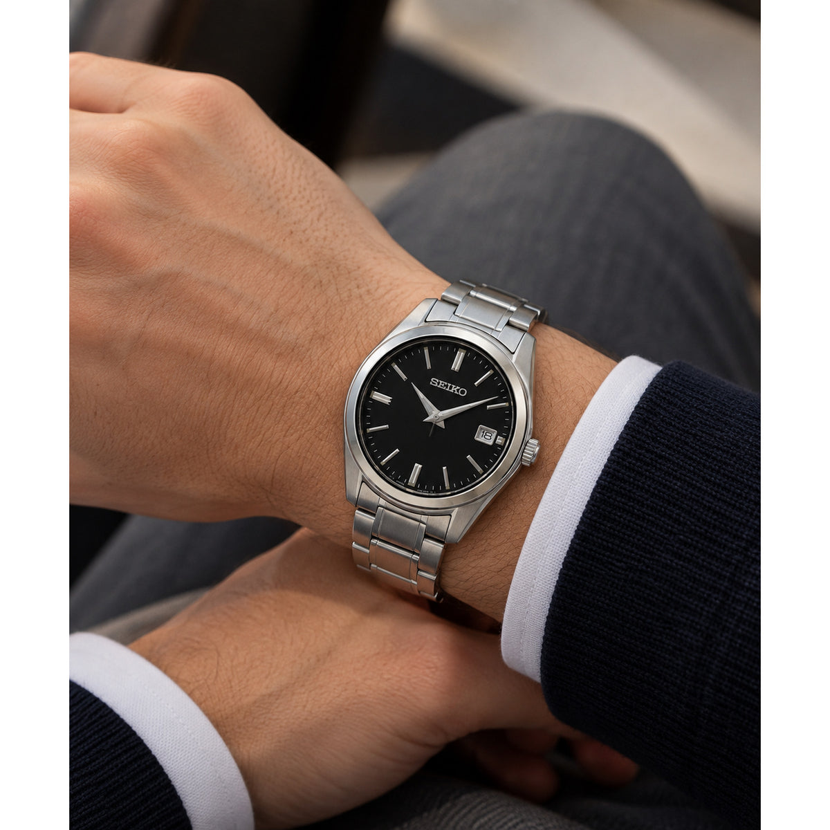 Seiko Essentials SUR311 men's quartz watch featuring a black dial and stainless steel bracelet, worn on the wrist