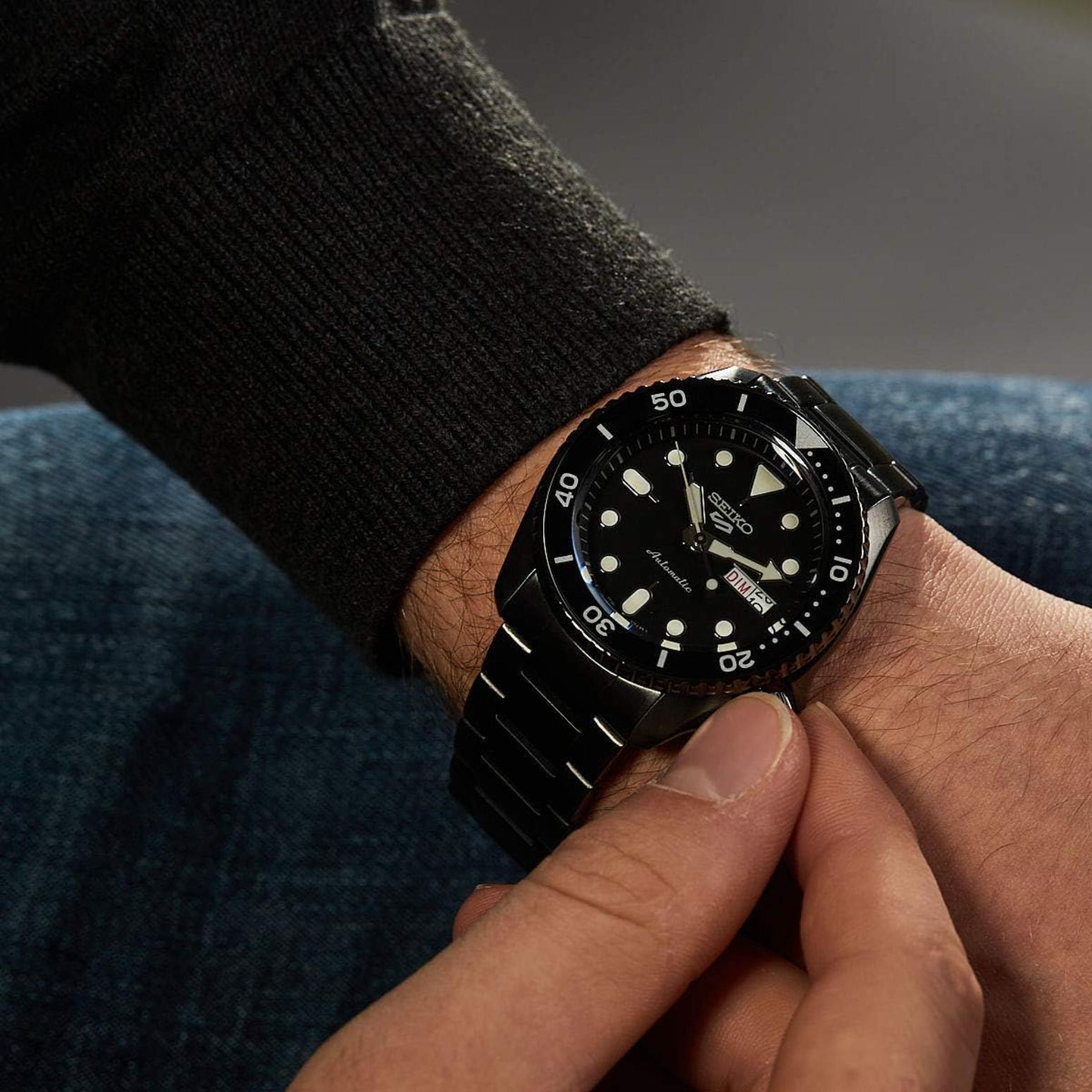Seiko SRPD65K1 mens automatic dive watch with black dial and bracelet worn on wrist in close up detail