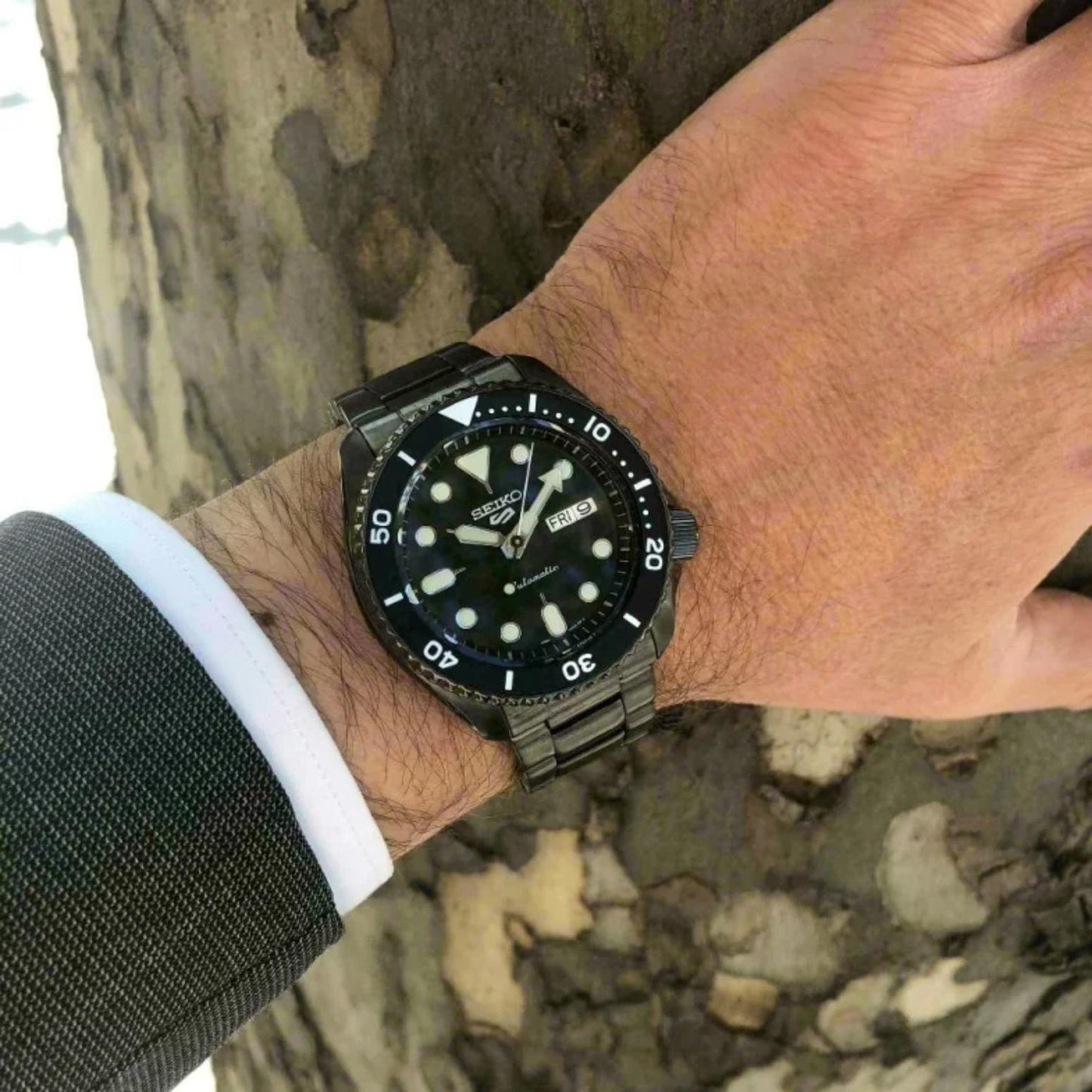 Seiko SRPD65K1 mens automatic dive watch with black dial and black stainless steel bracelet worn on wrist outdoors