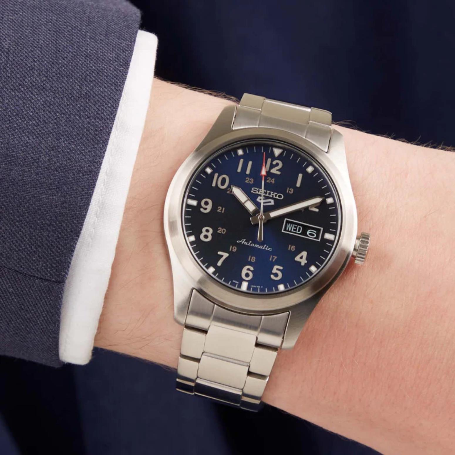 Seiko SRPG29K1 mens automatic field watch with blue dial and stainless steel bracelet worn on wrist in smart casual style