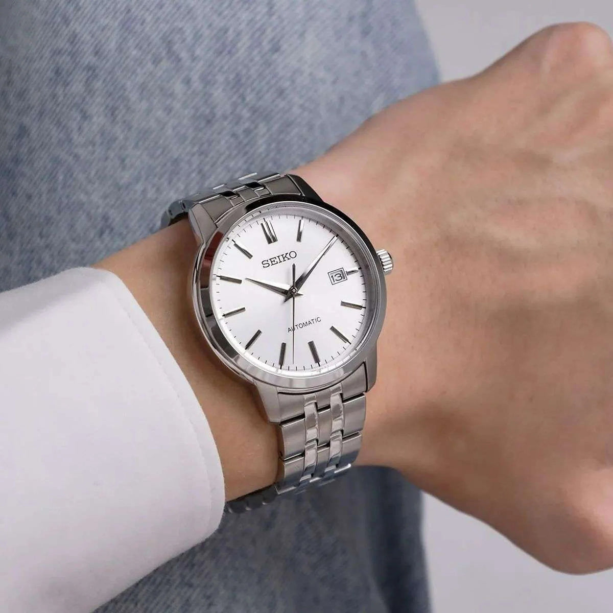 Seiko Essentials SRPH85K1 automatic watch featuring a silver dial and stainless steel bracelet on a wrist