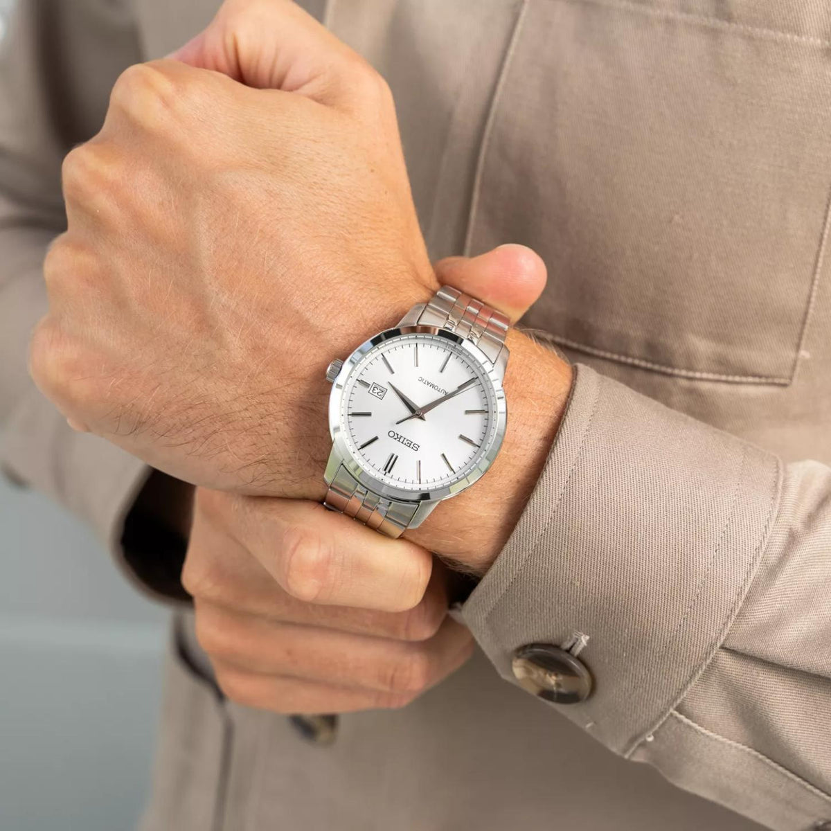 Seiko Essentials SRPH85K1 men's automatic watch with silver dial and stainless steel bracelet worn on wrist