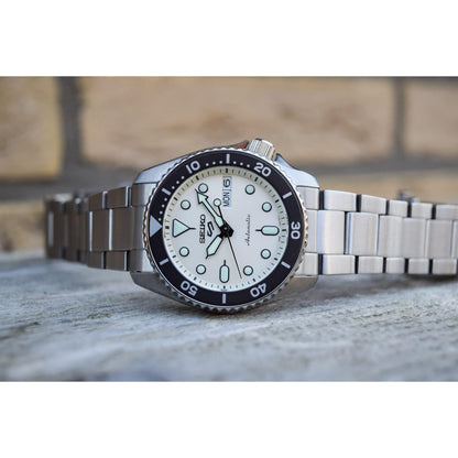 Seiko SRPK31 automatic dive watch with cream dial, rotating bezel, luminous markers and stainless steel bracelet shown in close-up.