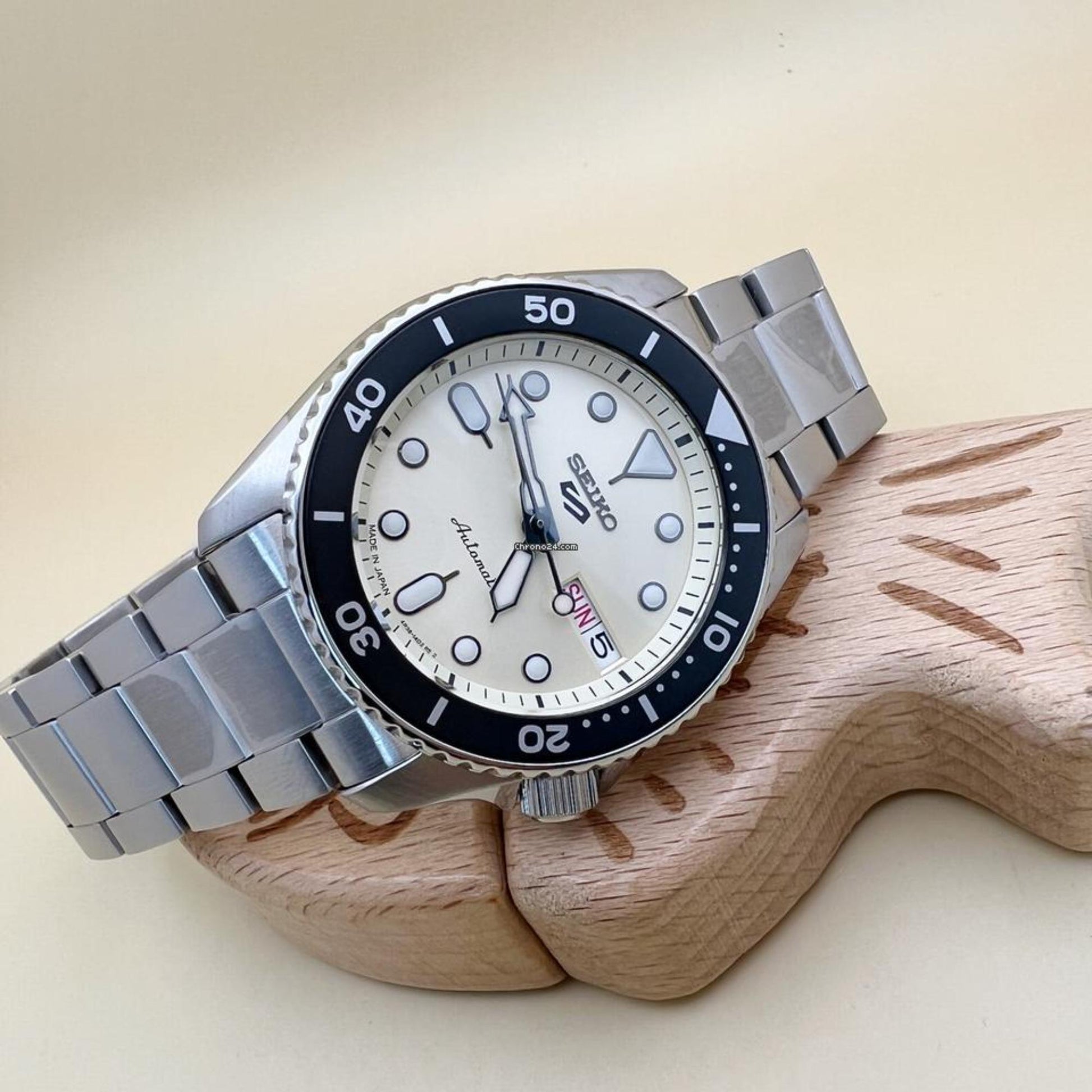 Seiko SRPK31 automatic dive watch with cream dial, rotating bezel and stainless steel bracelet displayed in lifestyle setting.