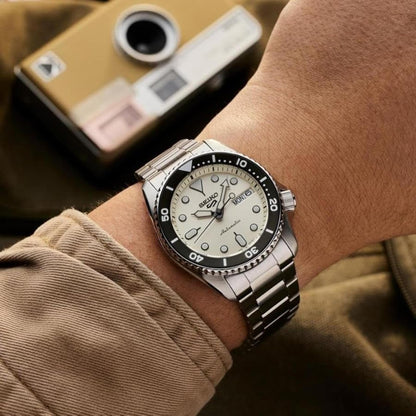 Seiko SRPK31 automatic dive watch worn on the wrist with cream dial, rotating bezel, day and date display and stainless steel bracelet.