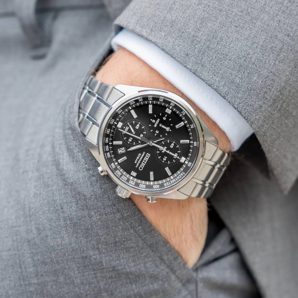 Seiko SSB379 men's quartz chronograph watch featuring a black dial and stainless steel bracelet worn on the wrist with a grey suit.