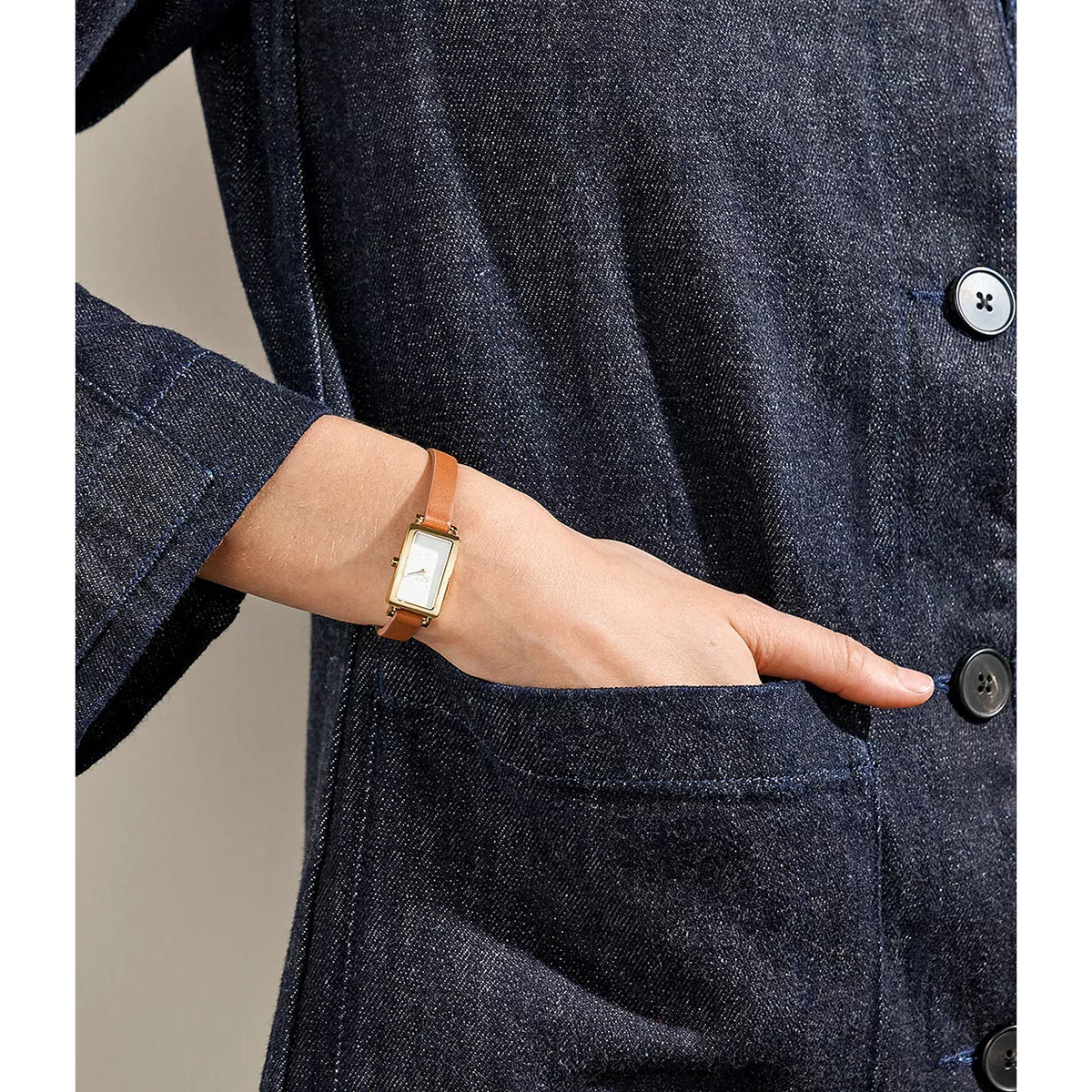 Skagen Hagen Micro SKW3149 women's quartz watch featuring a rectangular gold-tone case and brown leather strap, worn on a wrist against denim.