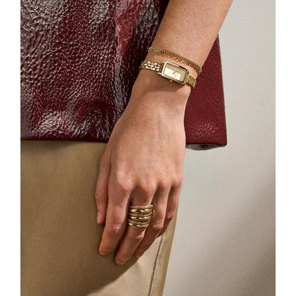 Skagen Hagen Micro SKW3154 women’s gold-tone dress watch with rectangular case and gold-tone bracelet worn on wrist in elegant lifestyle setting.