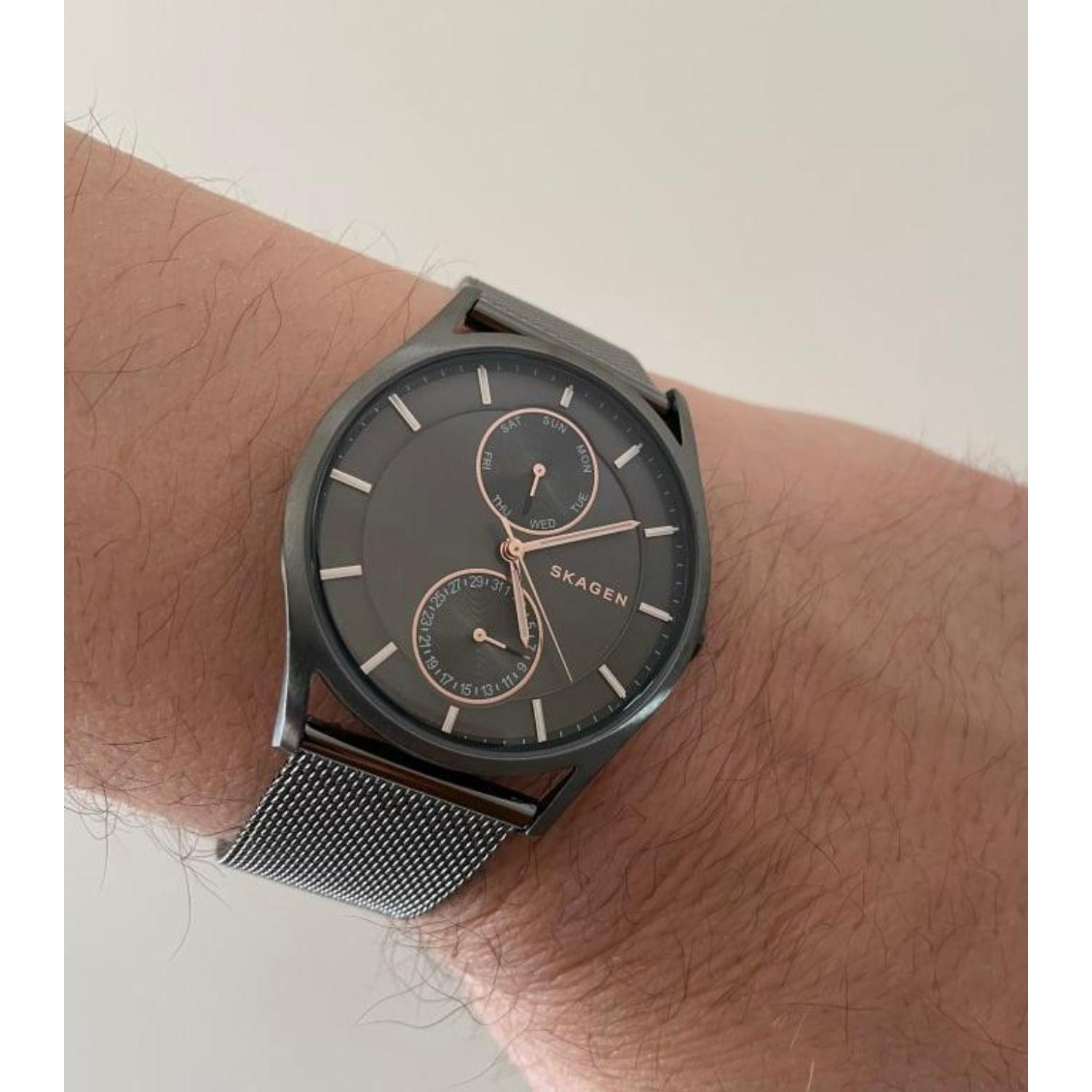 Skagen Holst SKW6180 multifunction watch with charcoal gray dial, rose gold-tone accents, black case, and black mesh bracelet worn on the wrist.