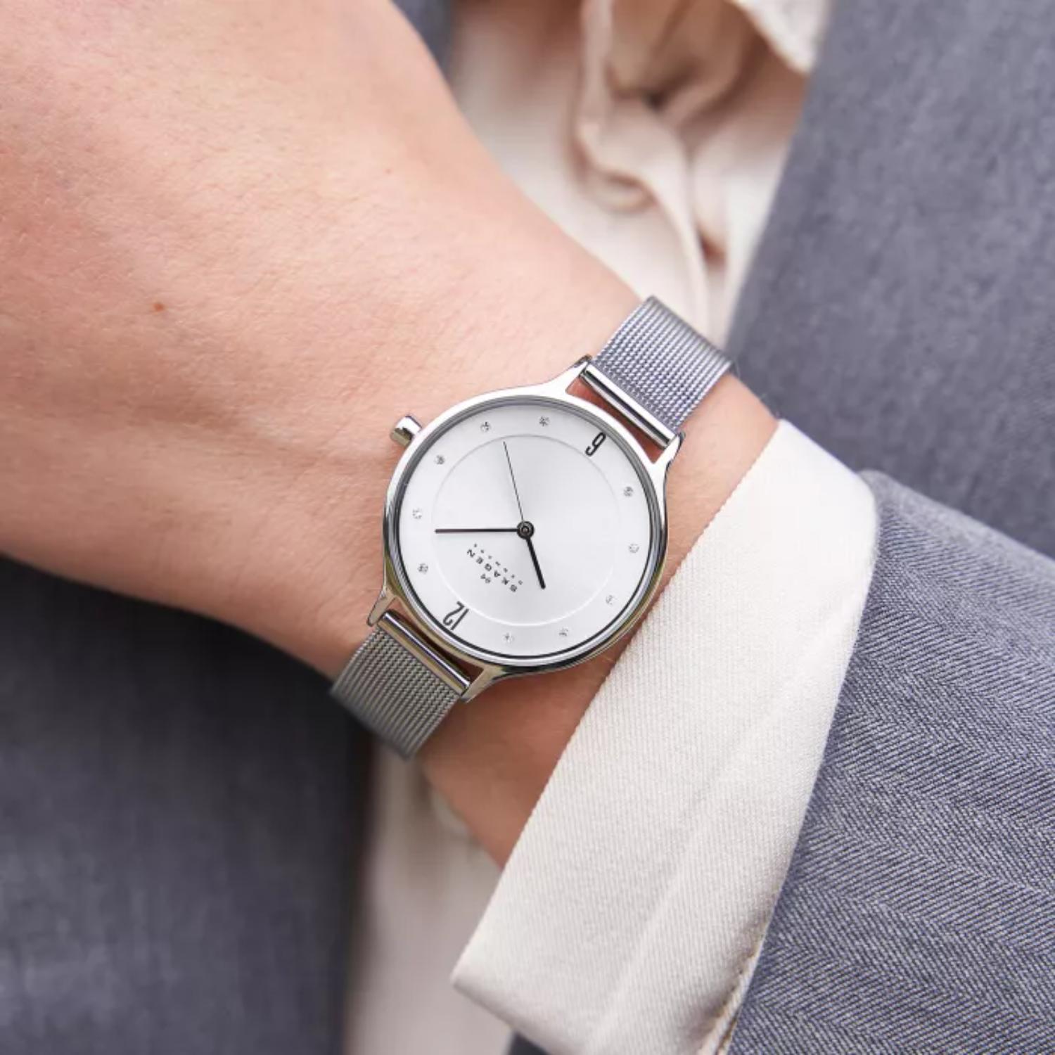 Skagen SKW2149 with white minimalist dial, crystal hour markers, polished silver-tone case, and stainless steel mesh bracelet worn on the wrist.