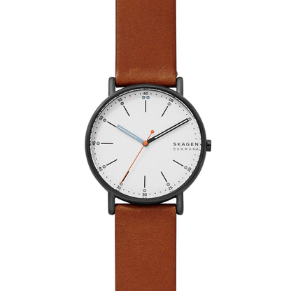 Skagen SKW6374 minimalist watch with white dial, black stick markers, gunmetal-tone case, orange seconds hand, and brown leather strap.