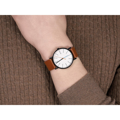 Skagen SKW6374 with white minimalist dial, gunmetal-tone case, orange seconds hand, and brown leather strap worn on the wrist in a casual style.