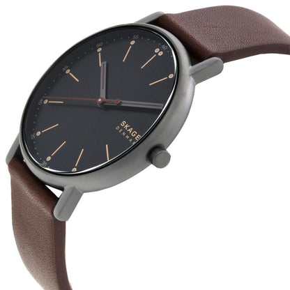 Skagen SKW6860 with black minimalist dial, slim gunmetal-tone case, rose gold-tone markers, and brown leather strap shown in a close-up angled view.