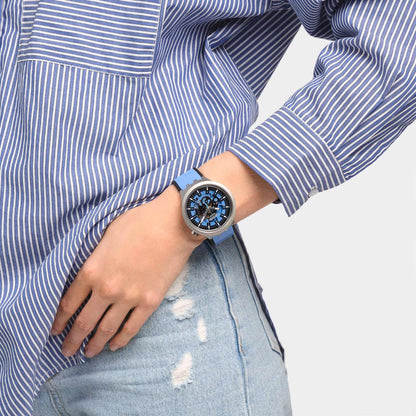 Swatch Big Bold Irony SB07S106 watch with a blue openworked dial, gray case, and blue strap worn on the wrist.