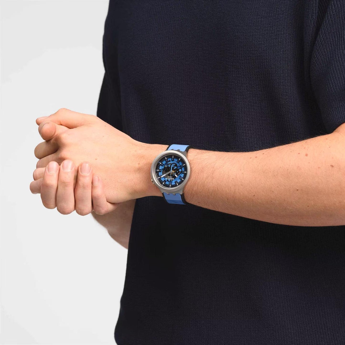 Swatch Big Bold Irony SB07S106 watch with a blue openworked dial, gray case, and blue strap worn on the wrist.