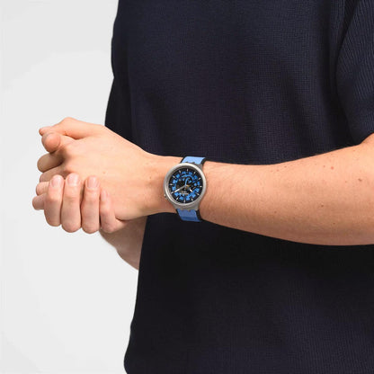 Swatch Big Bold Irony SB07S106 watch with a blue openworked dial, gray case, and blue strap worn on the wrist.