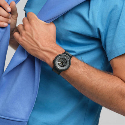 Swatch Big Bold Past the Horizon SB05B113 watch with a dark openworked dial, black case, white hour markers, and black strap worn on the wrist.