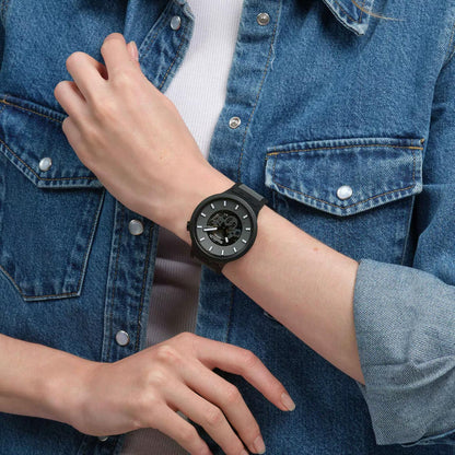Swatch Big Bold Past the Horizon SB05B113 watch with a dark openworked dial, black case, white hour markers, and black strap worn on the wrist.