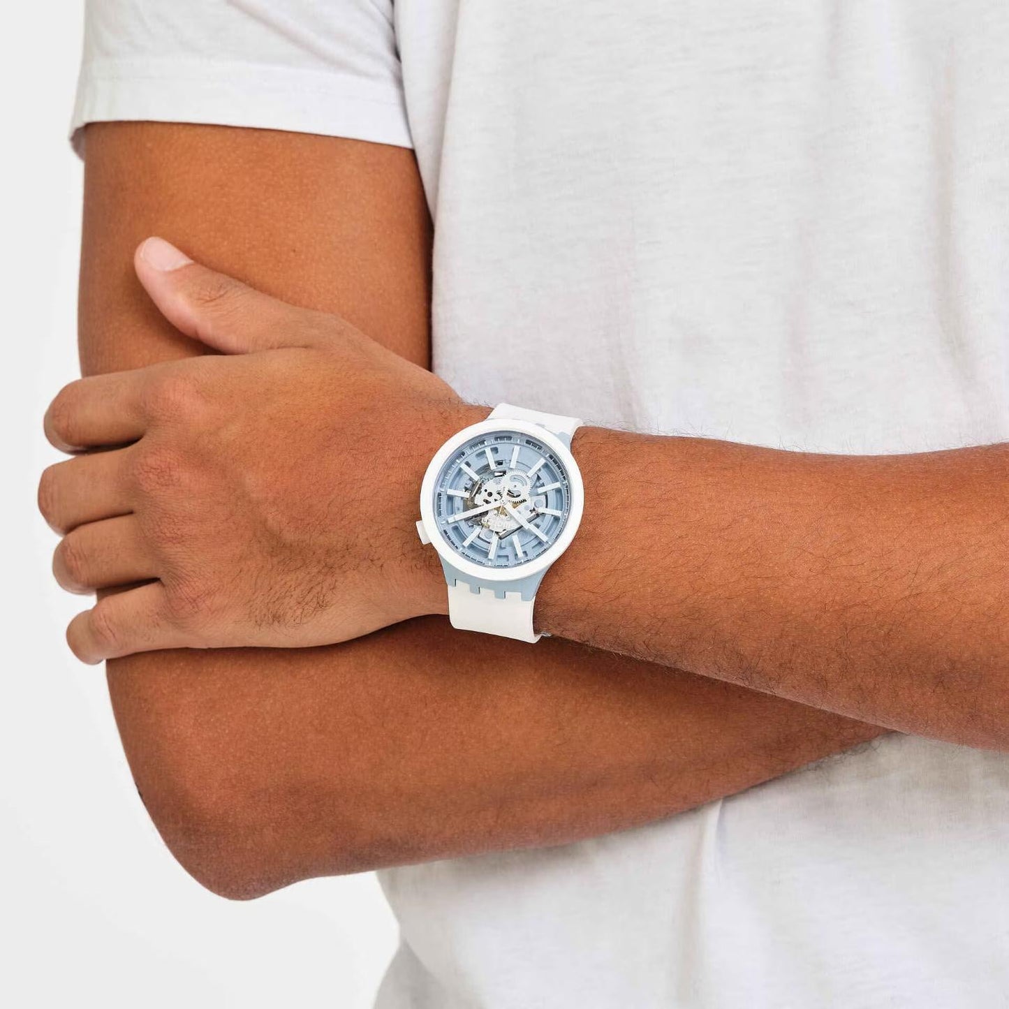 Swatch Big Bold Whice SB03N103 watch with a transparent blue openworked dial, white case, light blue accents, and white strap worn on the wrist.