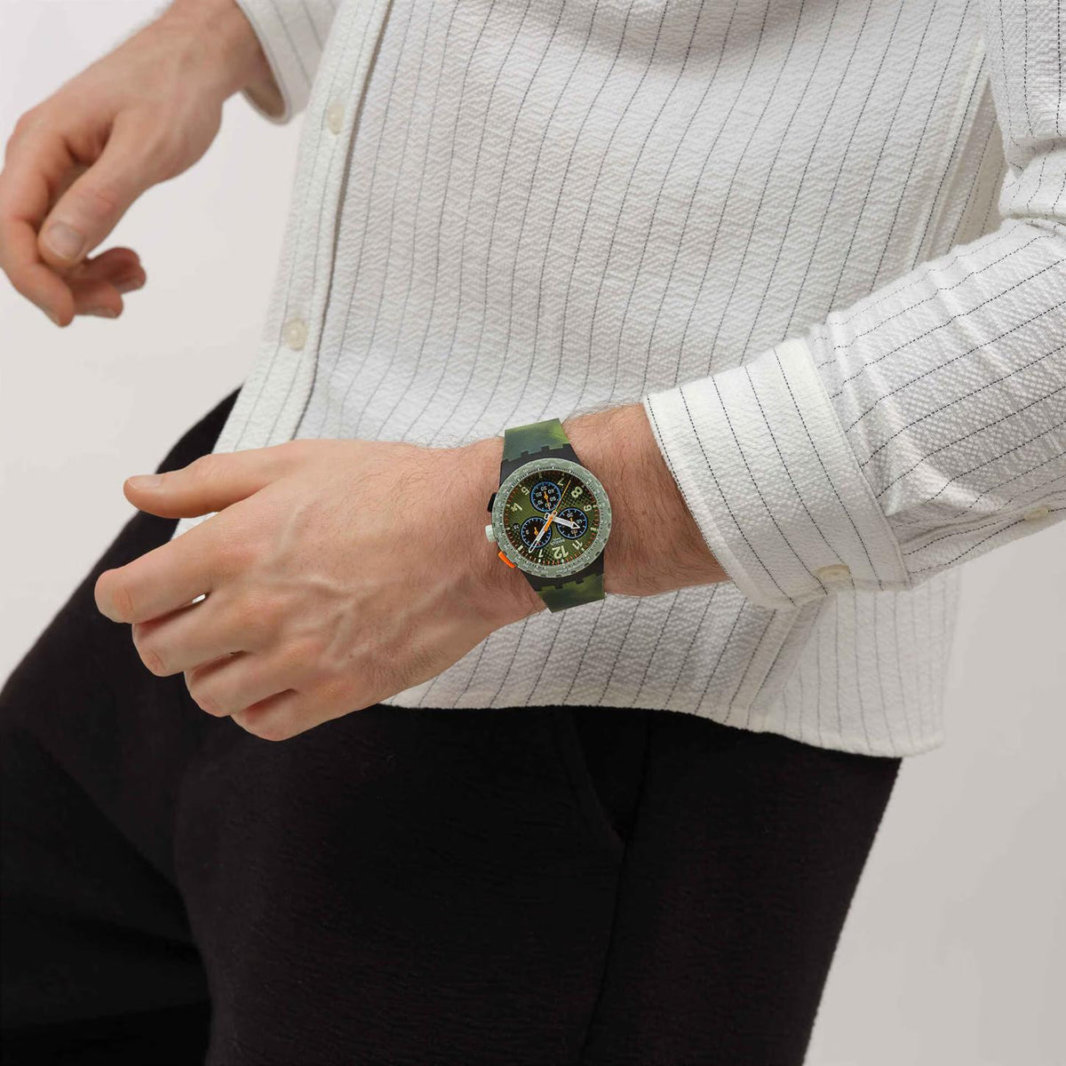 Swatch Midday Camo SUSB423 worn on the wrist with green chronograph dial, three subdials, orange accents, green tachymeter bezel, and matching textured green strap.