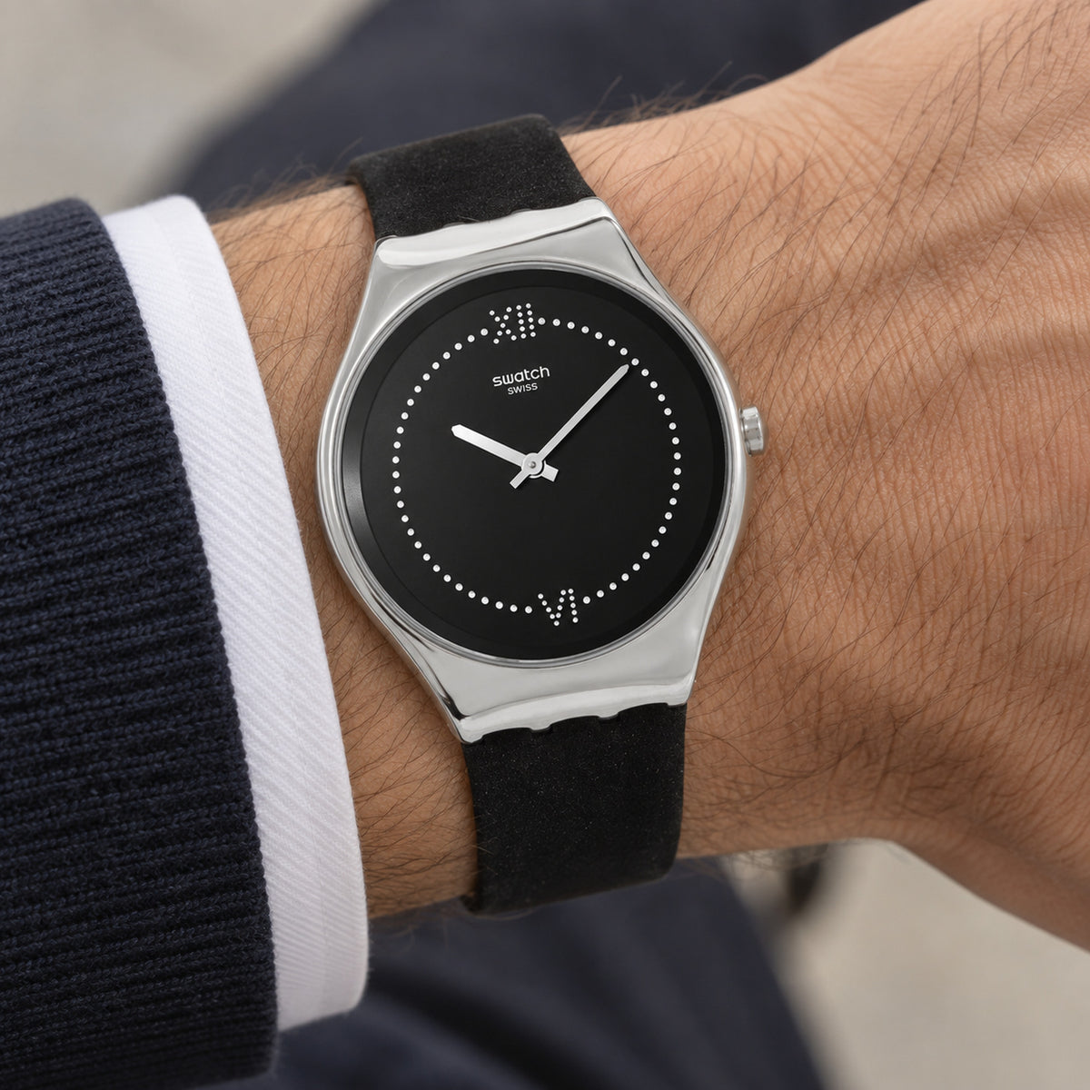 Swatch Skinalliage SYXS109 worn on the wrist with black dial, crystal-accented Roman numeral markers at 12 and 6, dotted hour track, polished silver-tone case, and black strap.