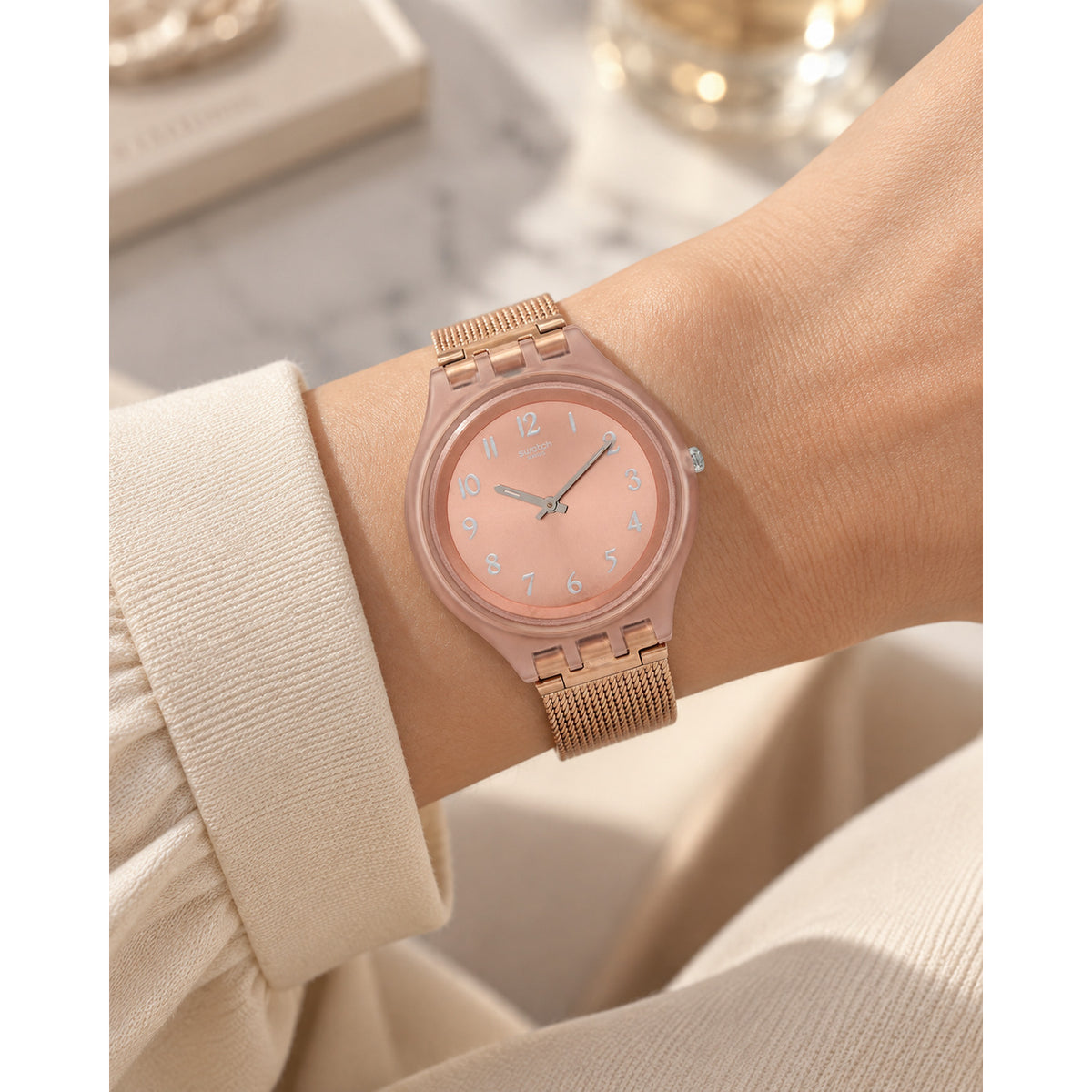 Swatch Skinchic SVUP100M worn on the wrist with rose gold-tone dial, silver-tone Arabic numerals and hands, matching rose gold-tone case, and fine mesh bracelet.