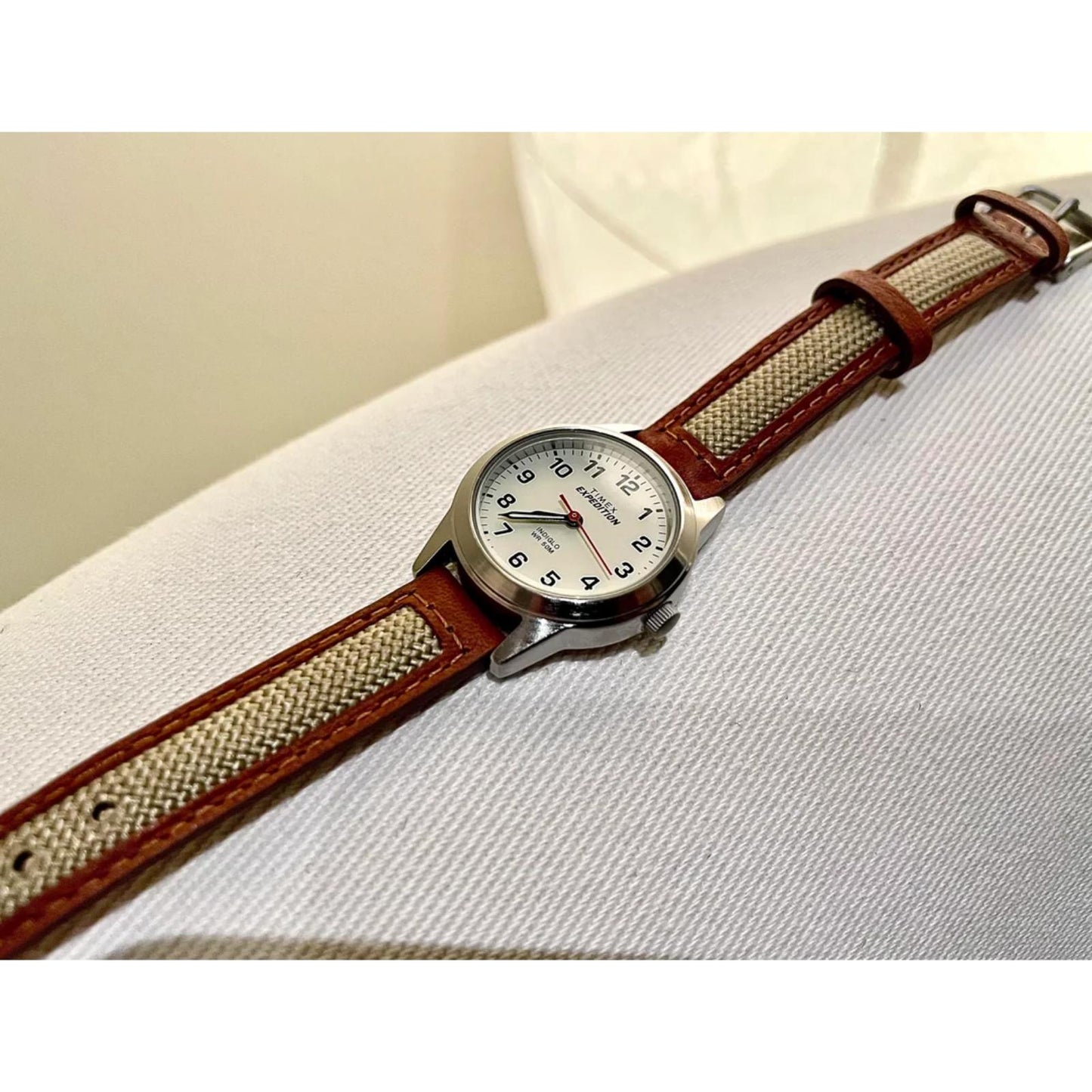 Timex Expedition Field Mini TW4B11900 women’s field watch with white dial, black Arabic numerals and beige fabric strap with brown leather trim.