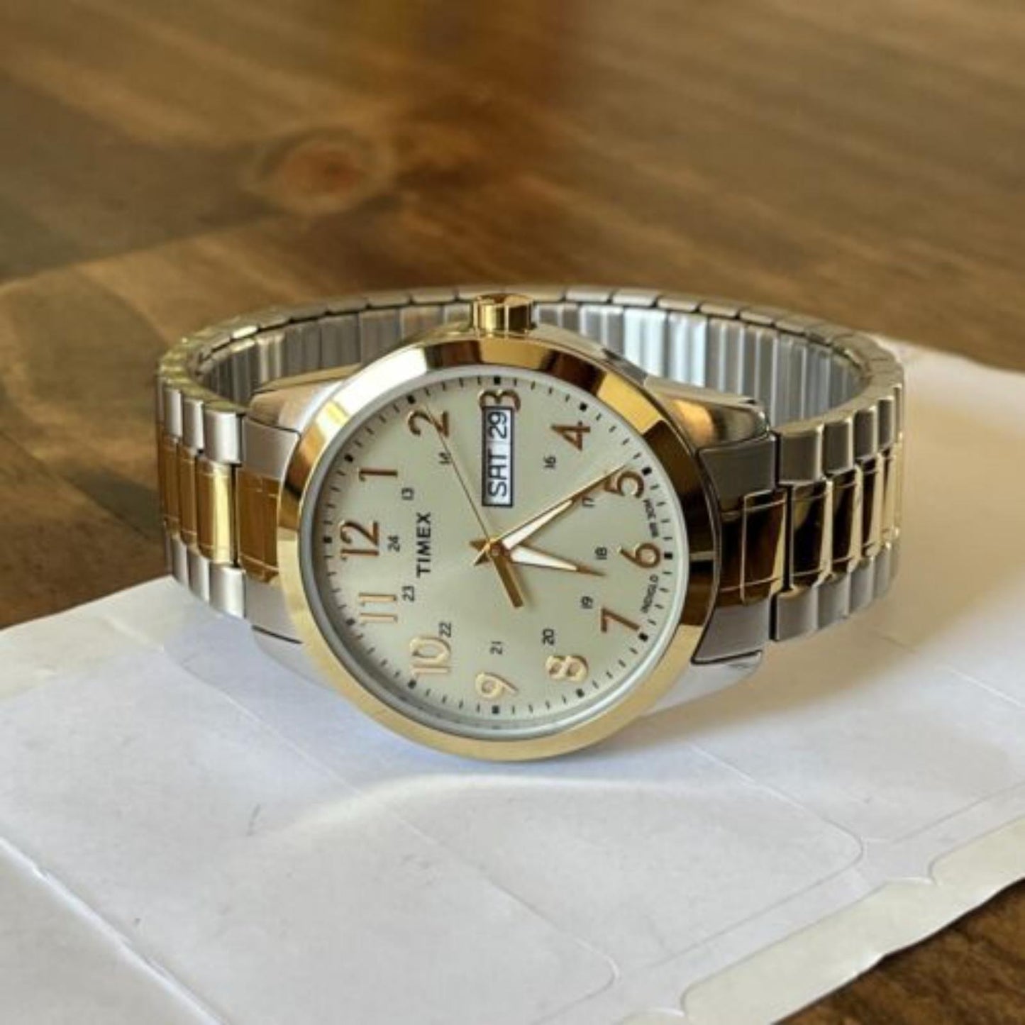 Timex South Street Sport T2M935 day-date watch with champagne dial and two-tone stainless steel expansion bracelet displayed on a wooden surface.