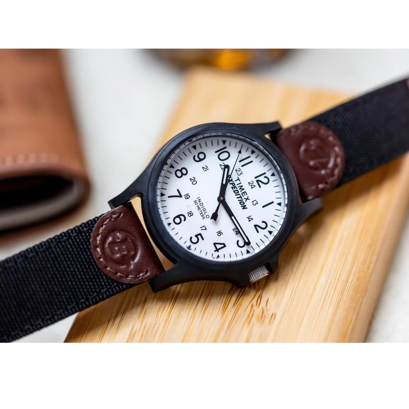 Timex TW4B08200 field watch with white dial, Arabic numerals, black case and brown leather and fabric strap shown in close-up.