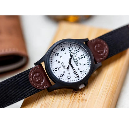 Timex TW4B08200 field watch with white dial, Arabic numerals, black case and brown leather and fabric strap shown in close-up.