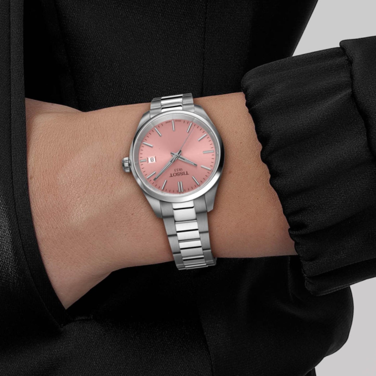 Tissot PR 100 T150.210.11.331.00 with pink sunray dial, slim stainless steel case, and polished steel bracelet worn on the wrist.