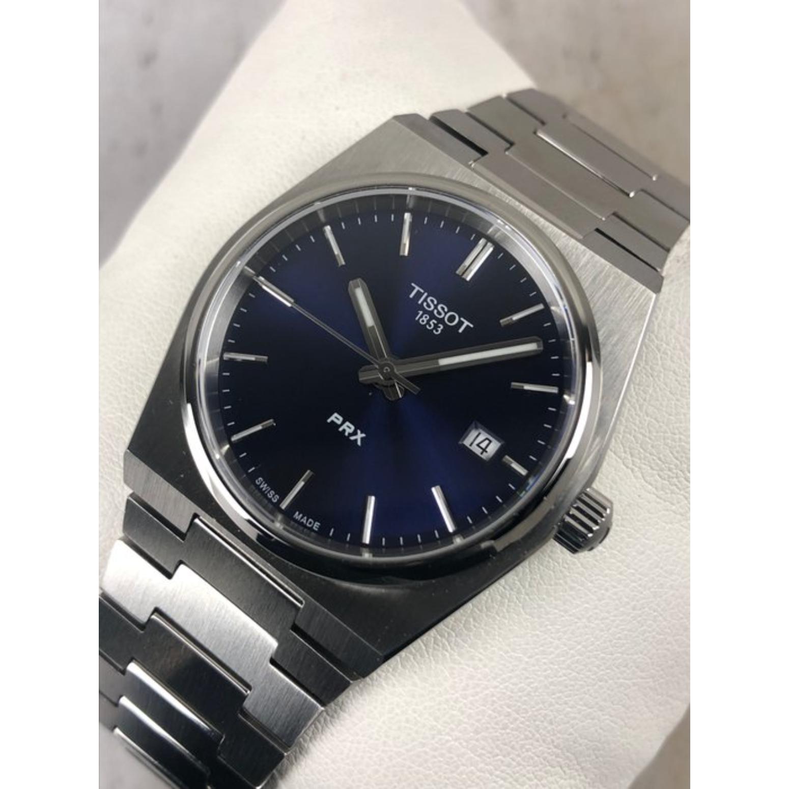 Tissot PRX T137.210.11.041.00 with blue sunray dial, silver-tone indexes, date window at 3 o’clock, and integrated stainless steel bracelet with brushed finish.