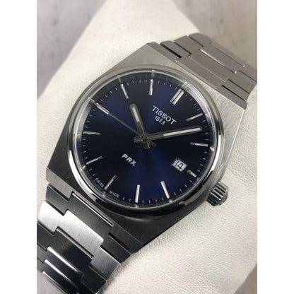 Tissot PRX T137.210.11.041.00 with blue sunray dial, silver-tone indexes, date window at 3 o’clock, and integrated stainless steel bracelet with brushed finish.