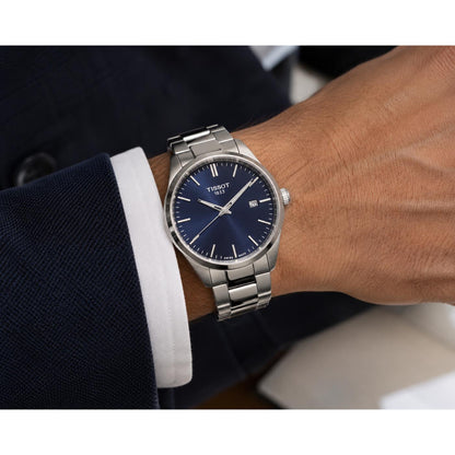Tissot T127.410.11.041.00 men’s watch with blue dial, silver-tone hour markers, date window at 3 o’clock, and metal bracelet worn on the wrist.