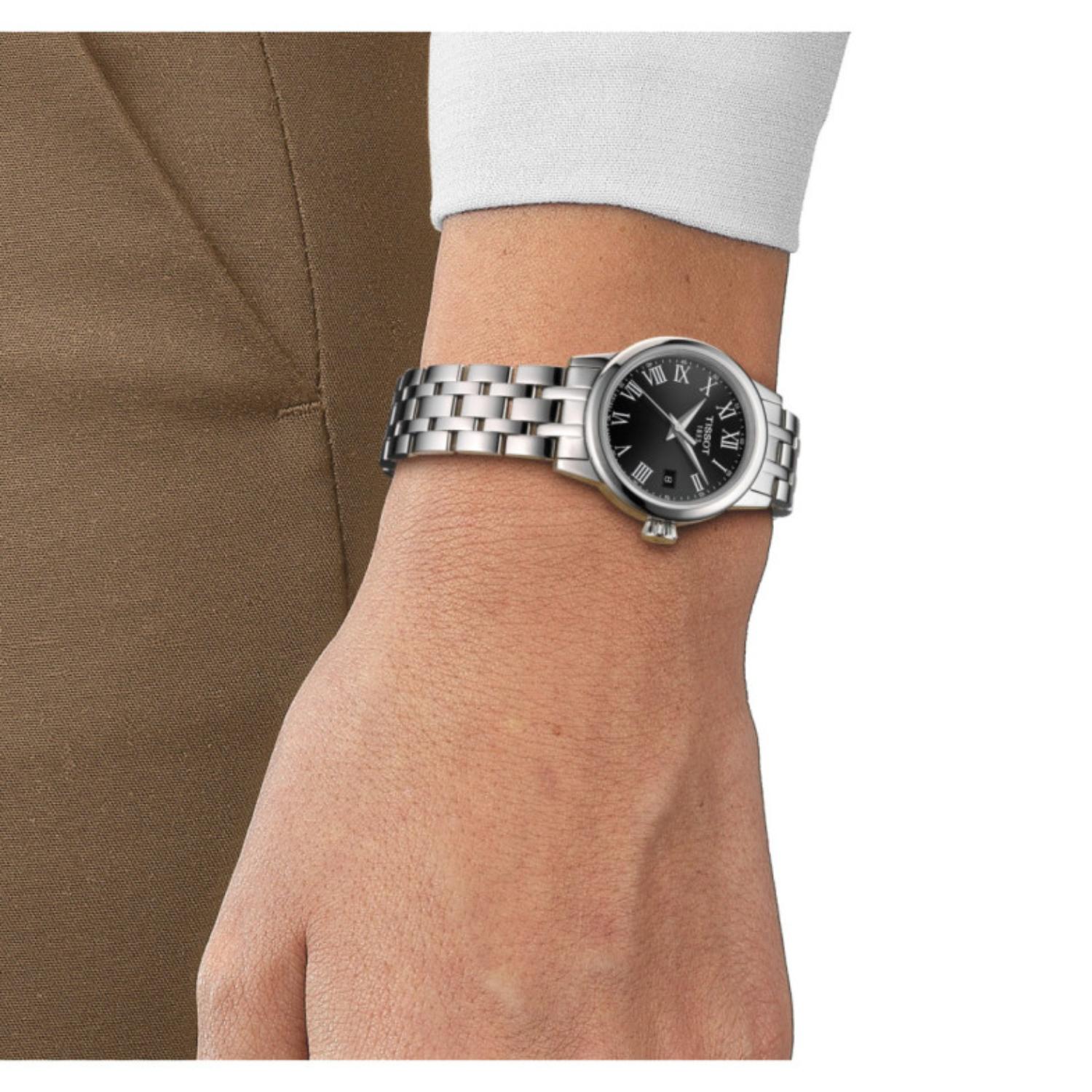 Tissot T129.410.11.053.00 quartz watch worn on the wrist with black dial, Roman numerals and stainless steel bracelet.