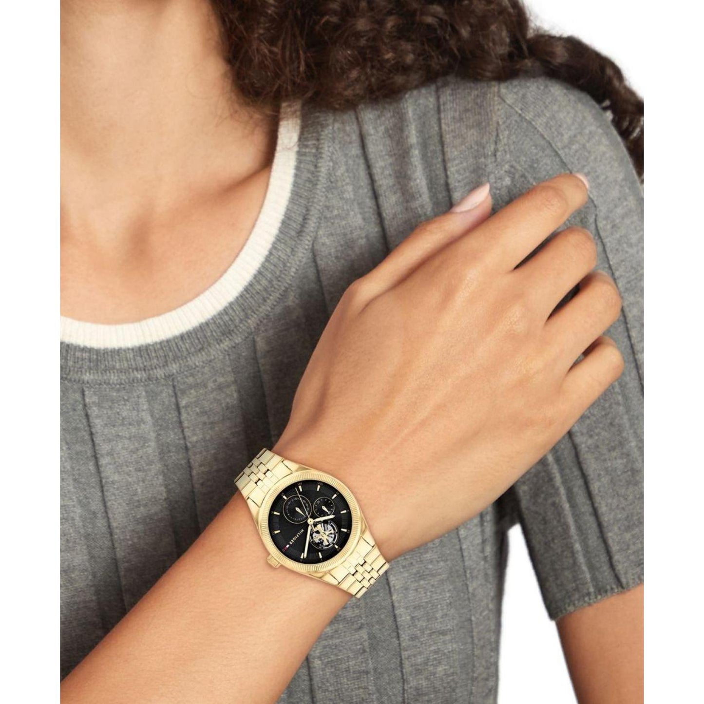 Tommy Hilfiger 1782717 women’s multifunction watch with black dial and gold-tone stainless steel bracelet worn on the wrist.